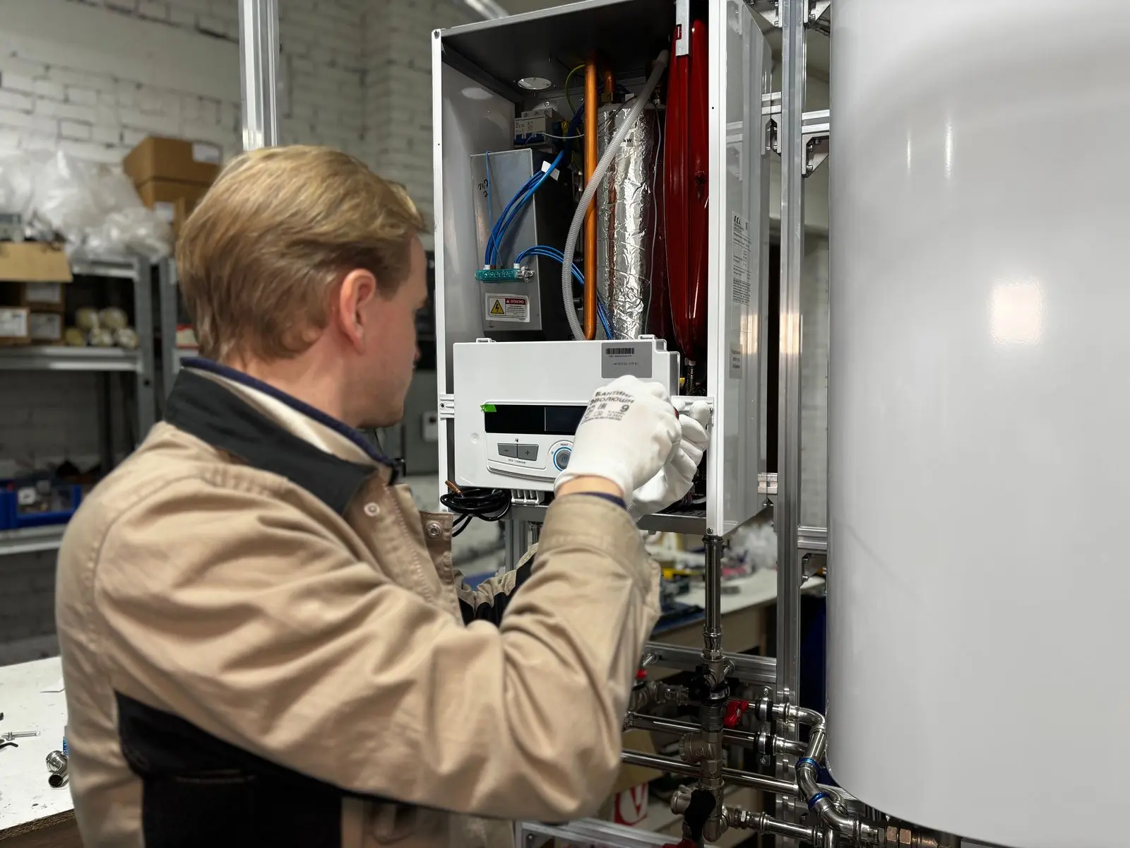 Technician connecting lines on a wall-mounted heating unit