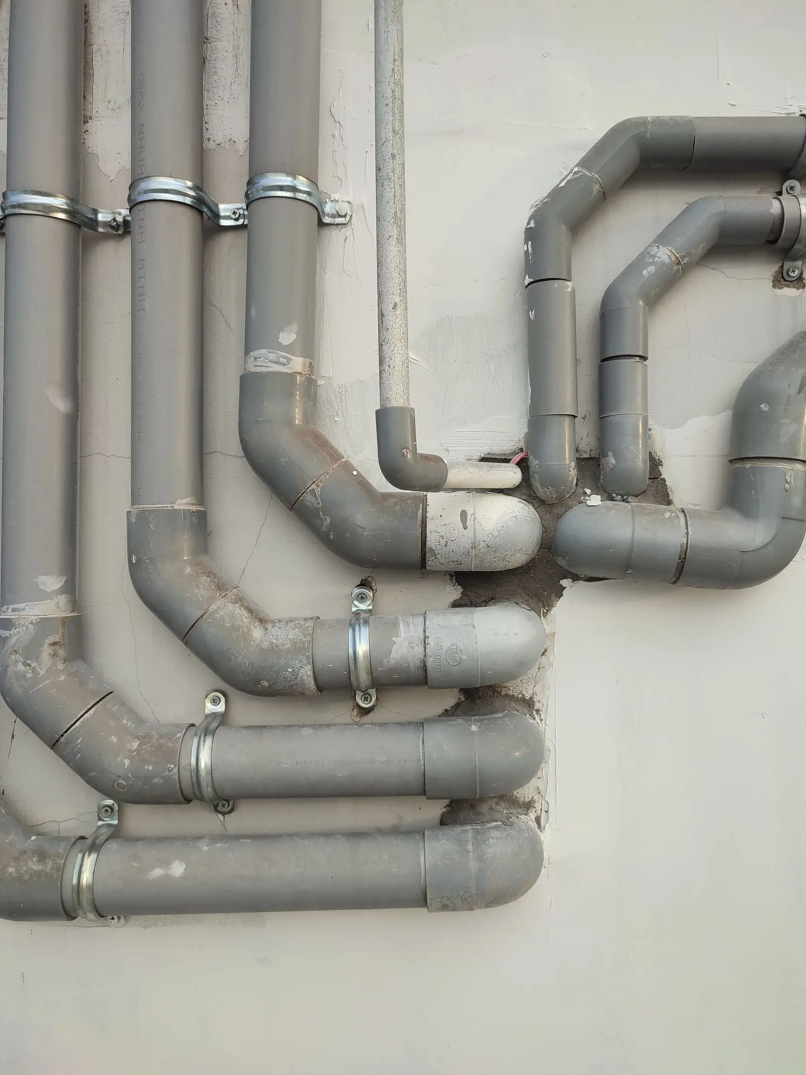 Gray plastic drain pipes clamped to an exterior wall