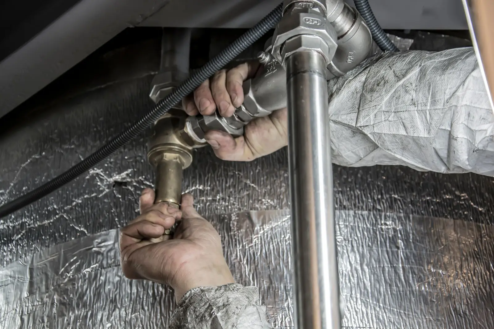 Hands tightening a brass fitting on a pipe